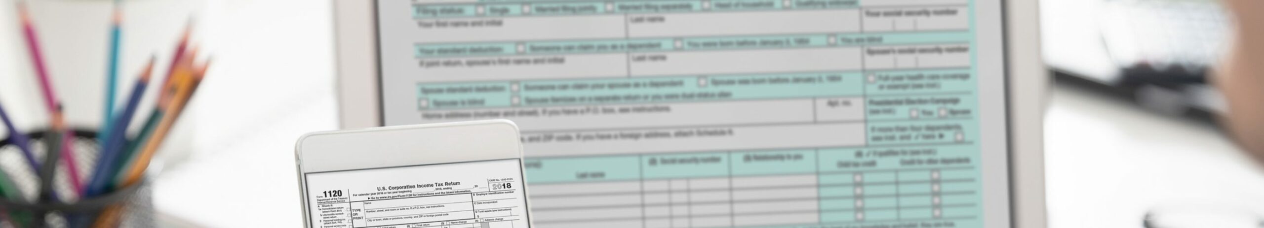 Accountant are filling online tax information using smartphone and laptop. Tax income concept.