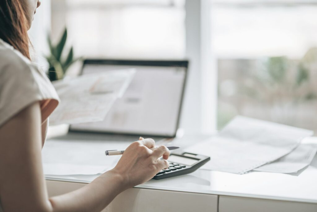 female doing taxes, calculator, computer