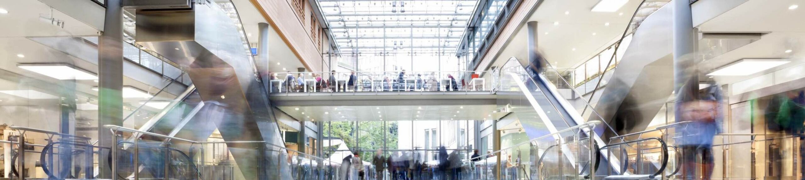 Large modern shopping mall with crowds of people walking.