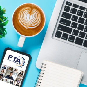FTA webinar, laptop, smart phone with FTA logo, coffee with foam heart, plant