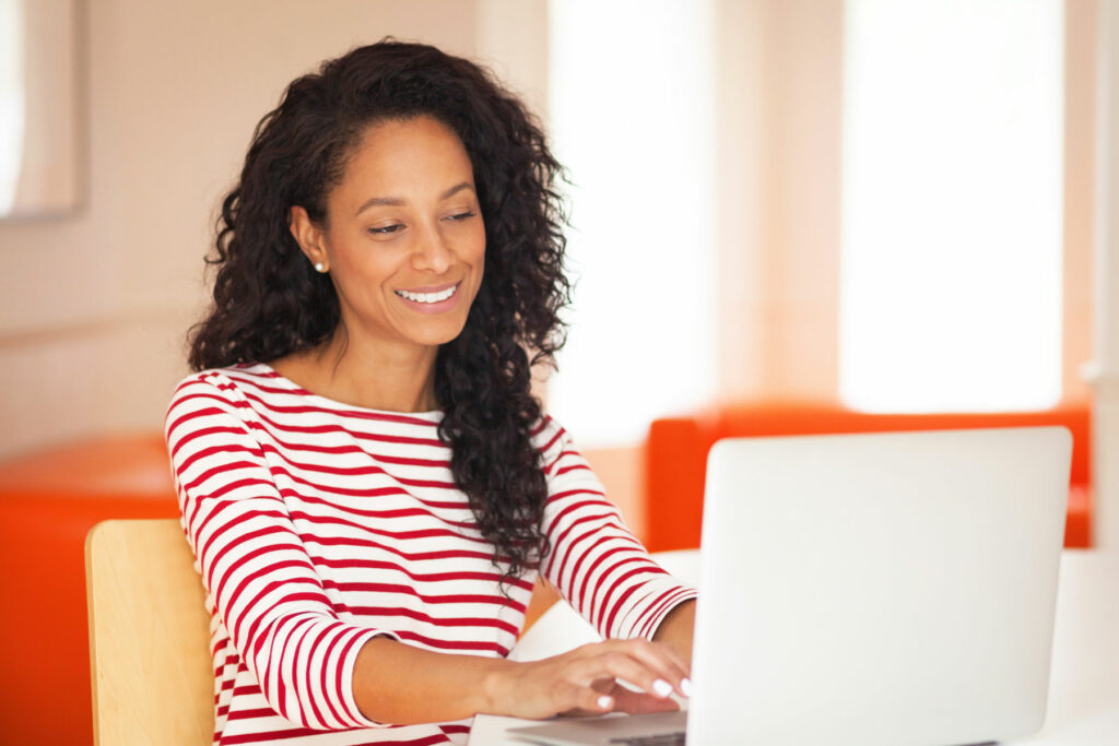 Woman working on laptop, smiling