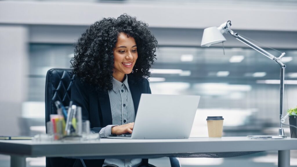 Modern Office: Businesswoman sitting at her desk working on a laptop computer.